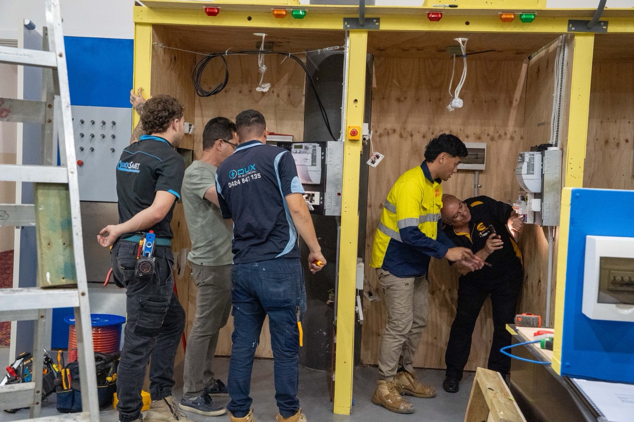 Electrical students diagnosing faults on training panels in a controlled learning environment