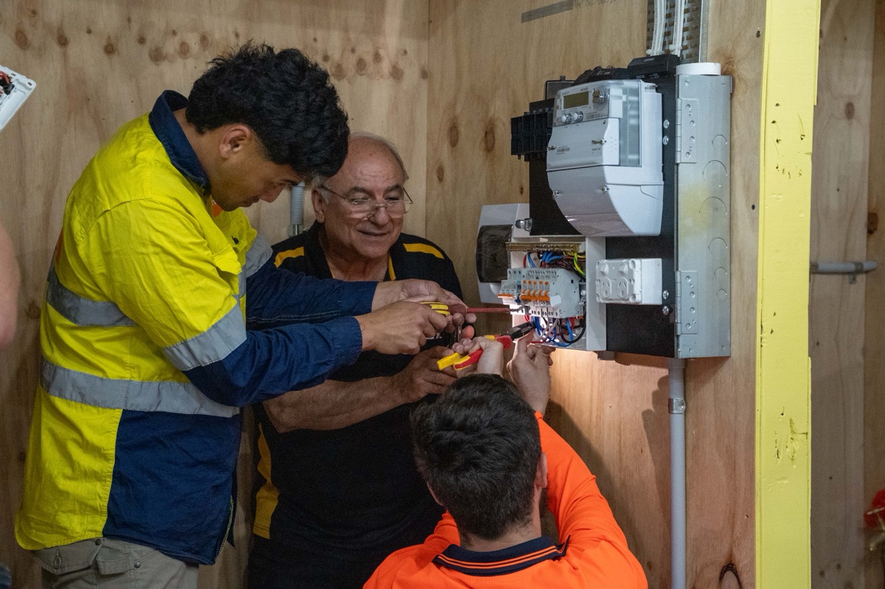 Electrical students completing structured wiring and fit-off training inside simulation bays